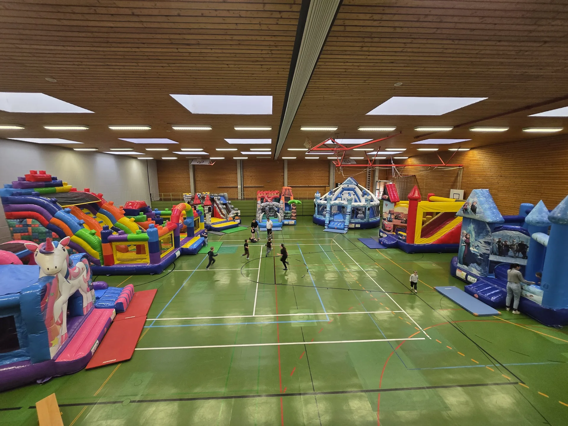 Übersicht über mehrere Hüpfburgen in einer Halle